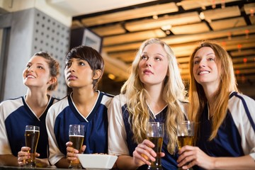 Female fan watching football at bar counter