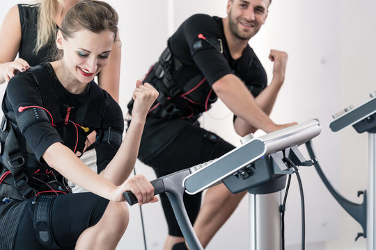Arm training in EMS gym, studio, trainer is helping sportive couple