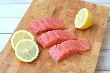 Raw salmon fillet with yellow lemon on brown wooden background