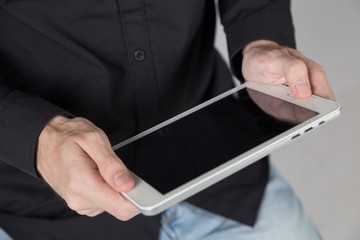 Young businessman holds tablet.