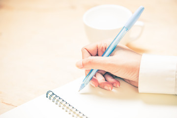 Business women hands working writing notebook on wooden desk, lighing effect