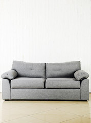 Grey sofa on a white wood wall texture background