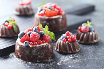 Sweet chocolate cakes with berries on black wooden table