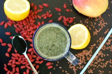Healthy fresh smoothie drink from red Chinese berry goji, lemon, green spirulina, linseed and apple