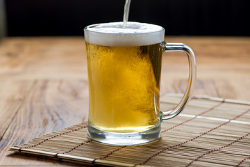 Beer pouring from top in bottle on wood table