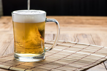 Beer pouring from top in bottle on wood table