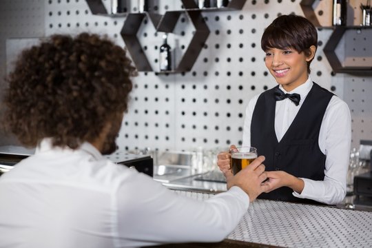 Barmaid serving drink to man
