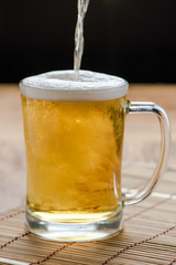 
Beer pouring from top in bottle on wood table