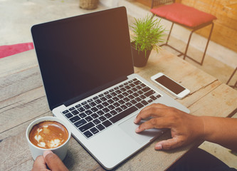 Man use laptop blank screen and holding coffee vintage tone.