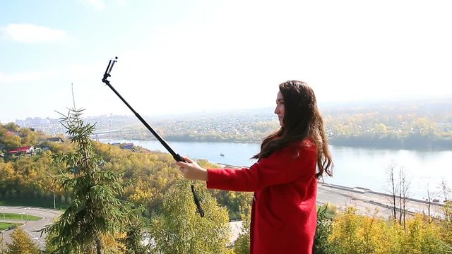 The girl in the red coat makes selfie with monopod