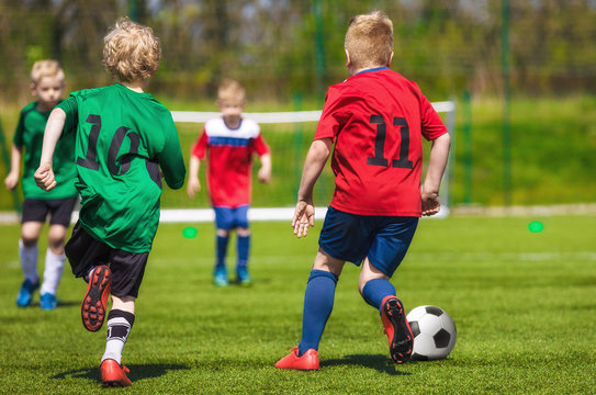 Young football soccer players running and kicking ball on sports field. Youth sport soccer league. Football match for children