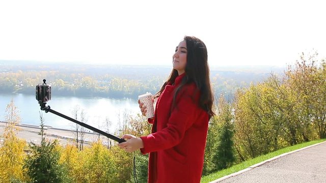 The girl in the red coat makes selfie with monopod