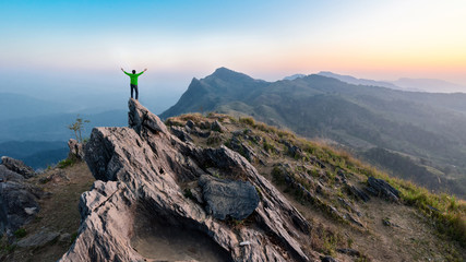 Fototapeta premium Winner man on peak of rocks mountain Hike at sunset, Active life