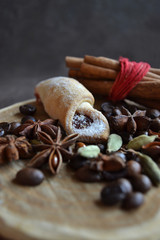 Winter treat. Rolled shortbread cookie, bunch of cinnamon sticks, coffee beans,flavors,anise stars, cardamom on rustic wooden tray. Christmas dessert. Shallow depth of field.