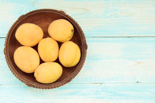Bowl of apricots on wooden blue background