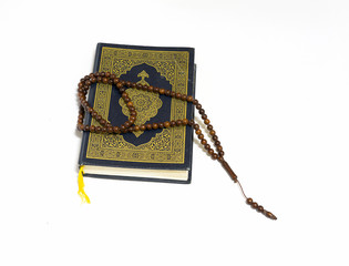 Quran - holy book of Muslims, and bead on white background