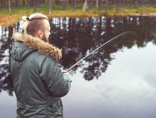 Hipster fisherman with a spinning rod catching fish