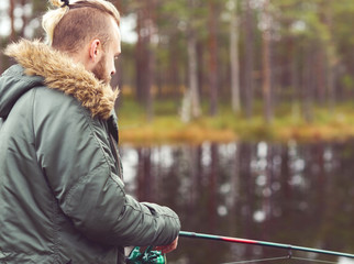 Fototapeta premium Hipster fisherman with a spinning rod catching fish