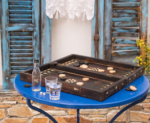 Backgammonspiel mit Aperitif vor alten blauen Fenster