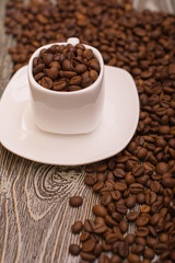 small white cup with coffee beans on wooden background