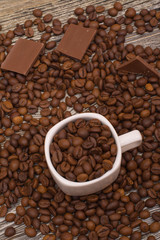 small white cup with coffee beans on wooden background