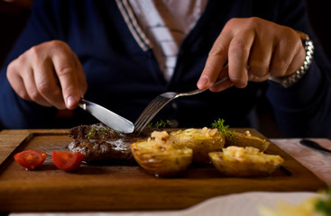 Man started eat medium roasted veal steak . Hands close-up view.