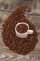 small white cup with coffee beans on wooden background