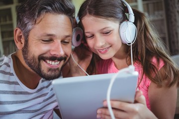 Father and daughter listening music on digital tablet