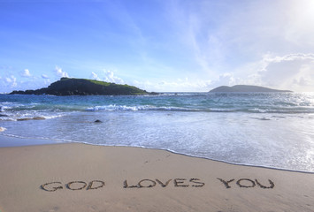 God Loves You written in sand on beach
