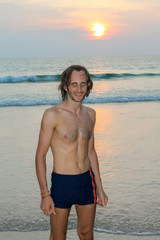 color portrait photo of handsome man looking up and smiling during the sunset at the beach.