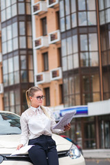 Business woman with papers near the car 