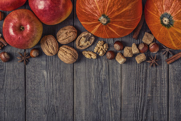 Wooden background with pumpkin, apples, nuts and spices.