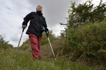 eine frau geht an krücken auf einem grasweg