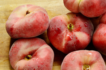 Dough nut peaches also known as Saturn peach with water drop on wooden board.
Benefits of Dough nut peaches. 
