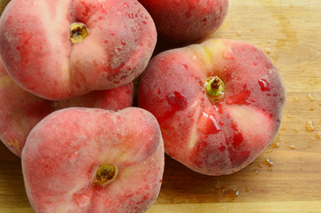 Dough nut peaches also known as Saturn peach with water drop on wooden board.
Benefits of Dough nut peaches. 
