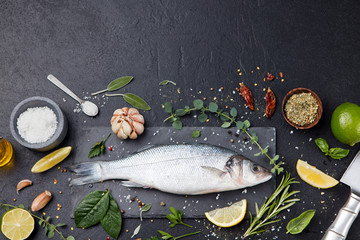 Raw fish, sea bass on slate black board Top view