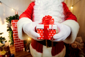 Gift red box with polka dots with a bow in the hands of Santa Cl