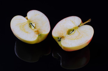 Two halves of a red apple on a black background.
