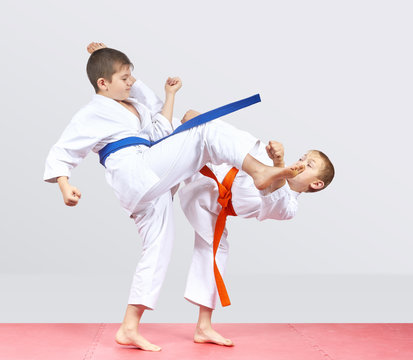 On a light background two boys are beating karate kicks