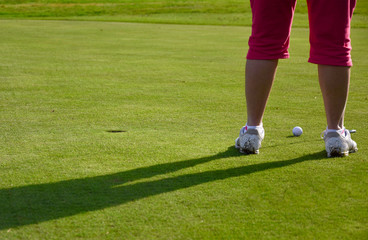 Obraz premium Woman lining up her golf putt on the green