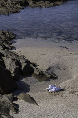 trainers on beach sand near a rock pool