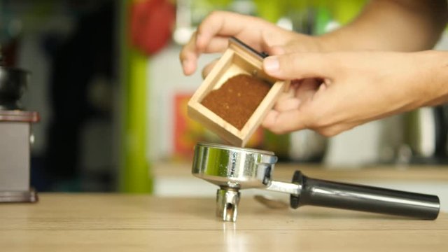Male hands pouring ground coffee from mill to a coffee machine holder. Dollyshot