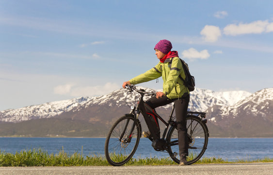 junge Frau sitzt auf Fahrrad vor Bergkulisse