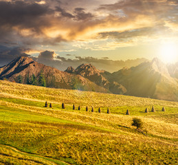 Naklejka premium Rural fields near the high mountains at sunset