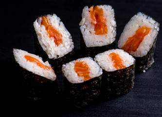 Japanese rolls with fish on a black background