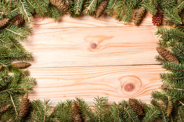 Fototapeta na wymiar frame of fir branches with cones on a light wooden background