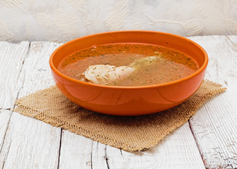 a bowl of chicken soup on a white wooden table