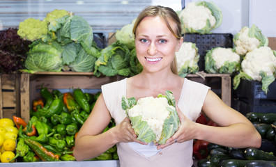 young woman buying cabbage at market.