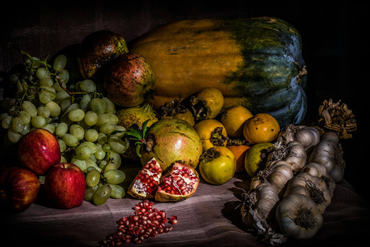 Still life. Fruits and vegetables typical of the fall season. Grapes, apples, squash, garlic, persimmon and pomegranate. There is life inside.