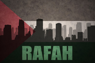 abstract silhouette of the city with text Rafah at the vintage palestinian flag background